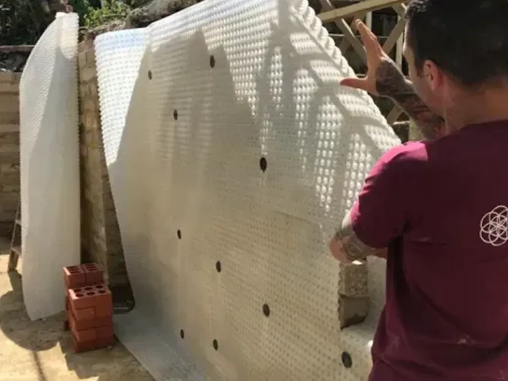 A man standing next to a white wall.
