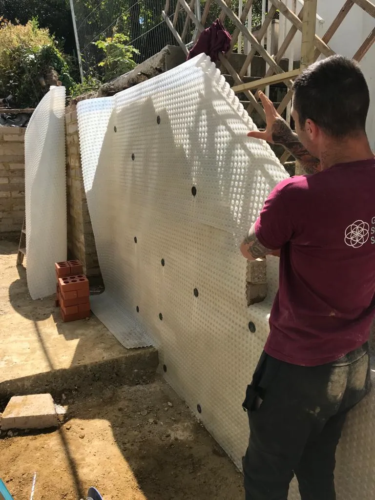 a man standing next to a wall with holes in it