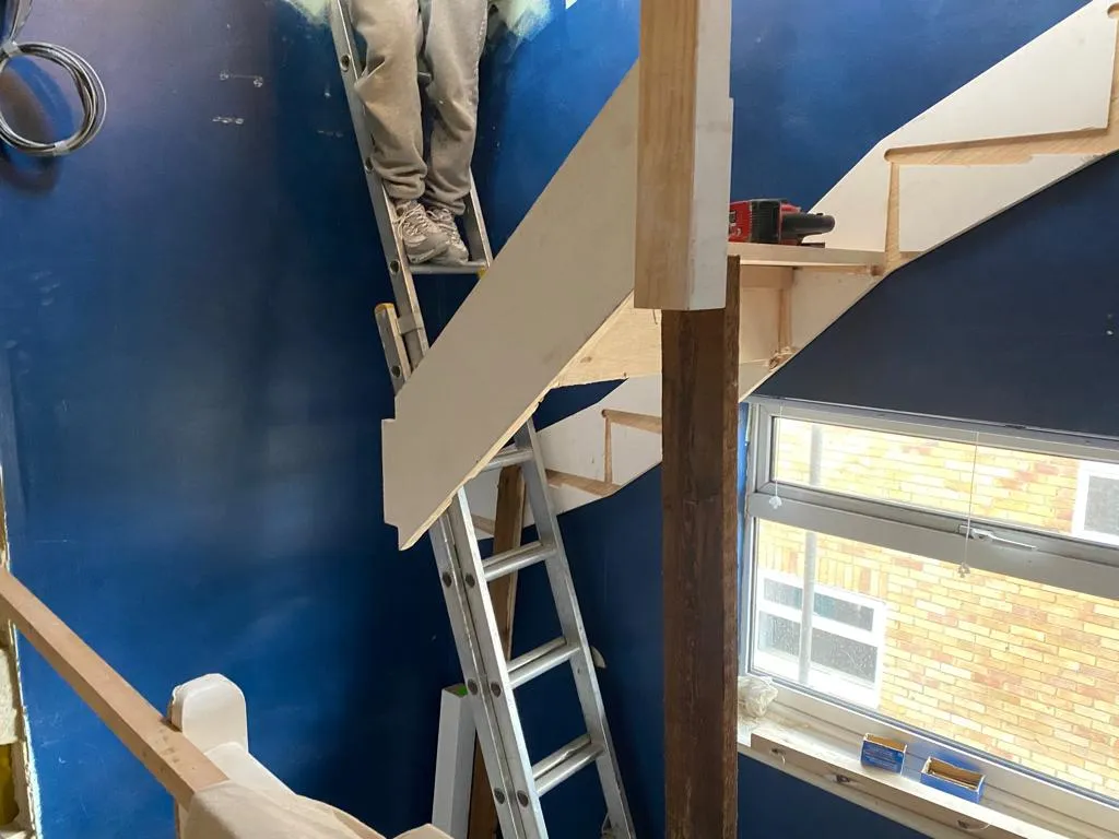 a man standing on a ladder painting a wall